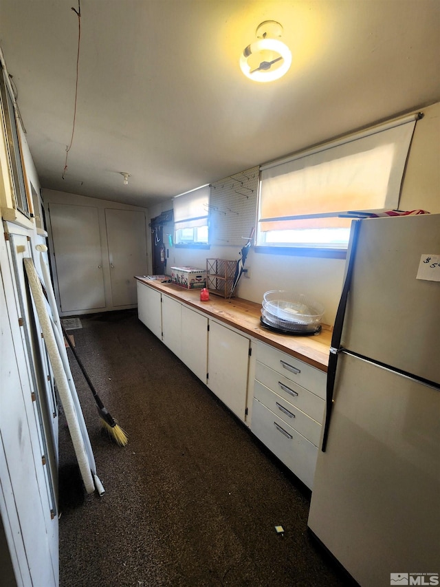kitchen with freestanding refrigerator, white cabinetry, and wood counters
