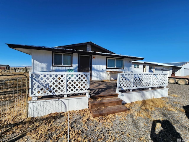 view of front of house with fence, a wooden deck, and board and batten siding