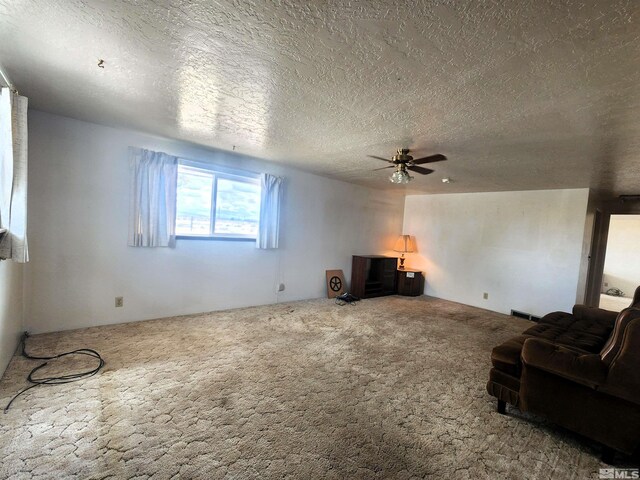 unfurnished living room with carpet, ceiling fan, and a textured ceiling