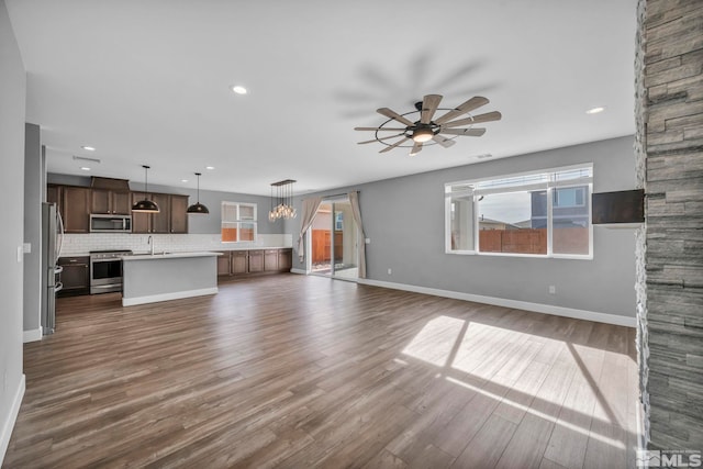 unfurnished living room featuring ceiling fan, sink, and dark hardwood / wood-style floors