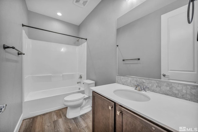 full bathroom featuring tasteful backsplash, bathing tub / shower combination, wood-type flooring, vanity, and toilet