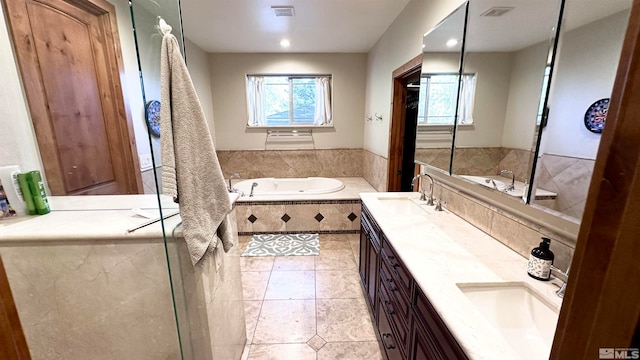 bathroom with tile patterned flooring, vanity, and tiled tub