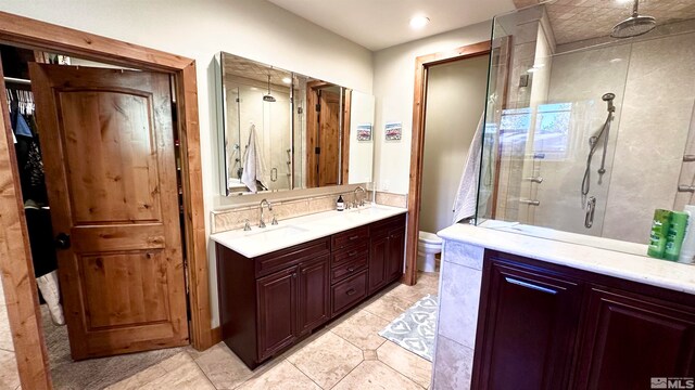 bathroom featuring toilet, tile patterned floors, vanity, and a shower with door