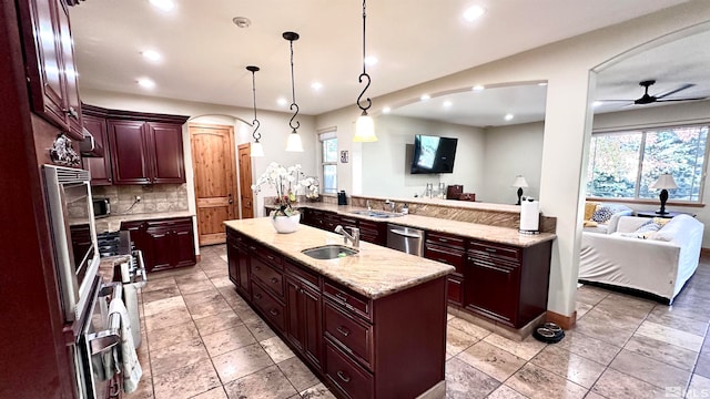 kitchen featuring appliances with stainless steel finishes, pendant lighting, sink, ceiling fan, and a kitchen island with sink