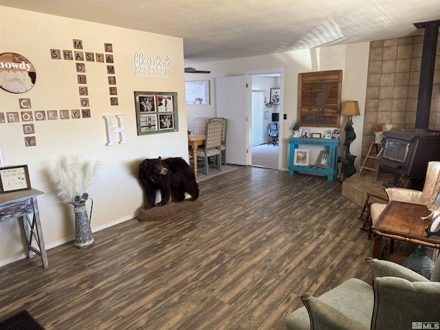 living room with a wood stove, a textured ceiling, and dark hardwood / wood-style floors