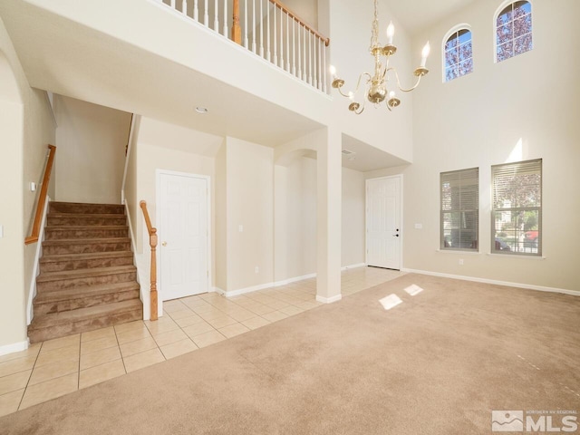 unfurnished living room with a high ceiling, light carpet, an inviting chandelier, and a wealth of natural light