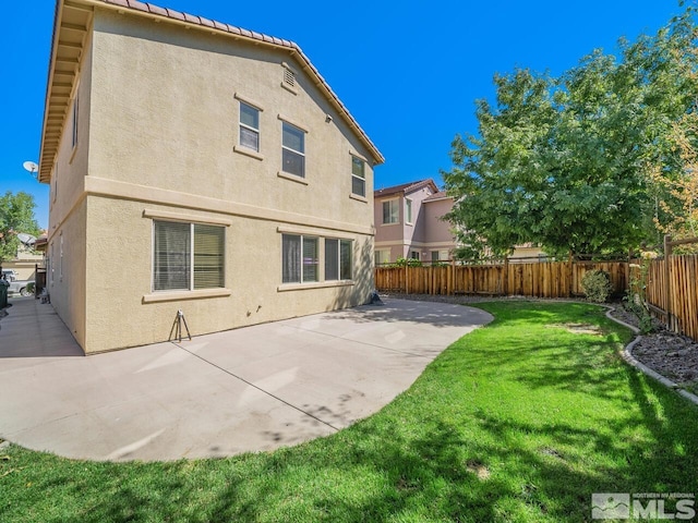 rear view of house featuring a yard and a patio