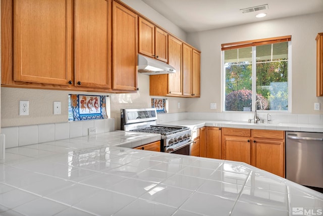 kitchen with sink, tile counters, and stainless steel appliances