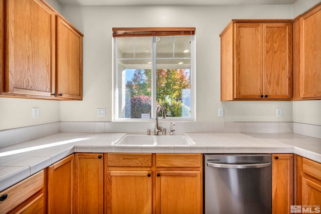 kitchen featuring stainless steel dishwasher, tile counters, and sink