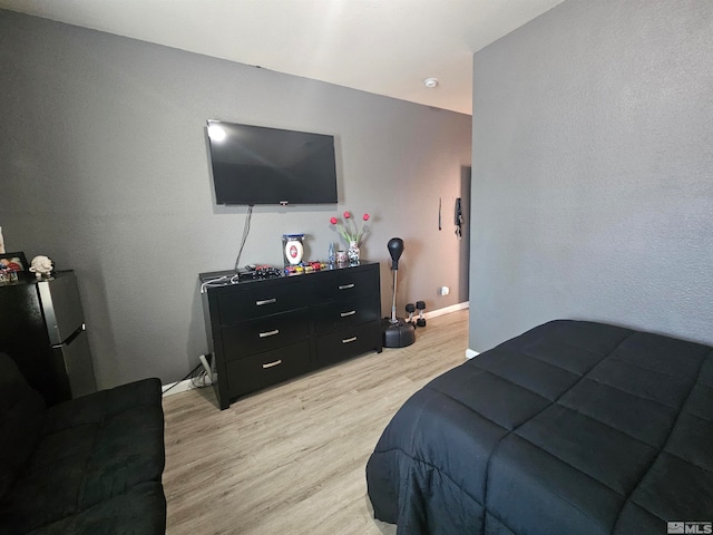 bedroom with stainless steel refrigerator and light wood-type flooring