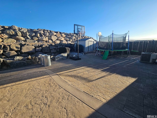 exterior space featuring a shed, cooling unit, and a trampoline