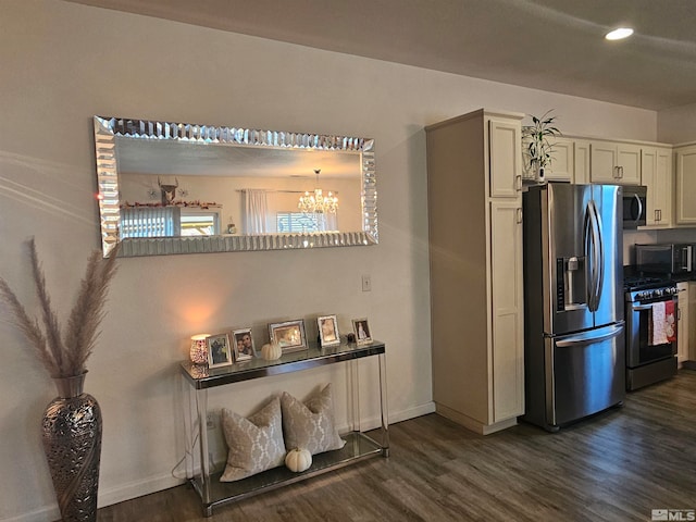 kitchen with kitchen peninsula, stainless steel appliances, a notable chandelier, and dark hardwood / wood-style flooring