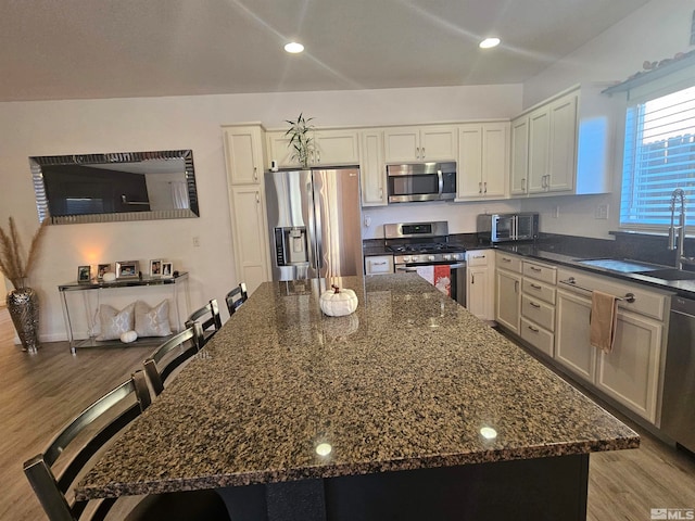 kitchen with a kitchen island, appliances with stainless steel finishes, sink, and light hardwood / wood-style flooring