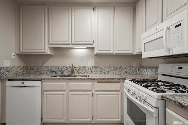 kitchen with white cabinetry, white appliances, sink, and light stone countertops