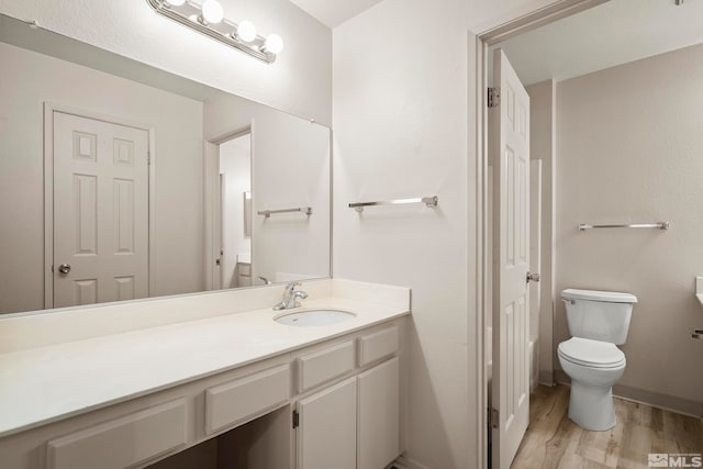 bathroom with hardwood / wood-style flooring, vanity, and toilet