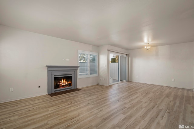 unfurnished living room featuring light hardwood / wood-style flooring and a notable chandelier