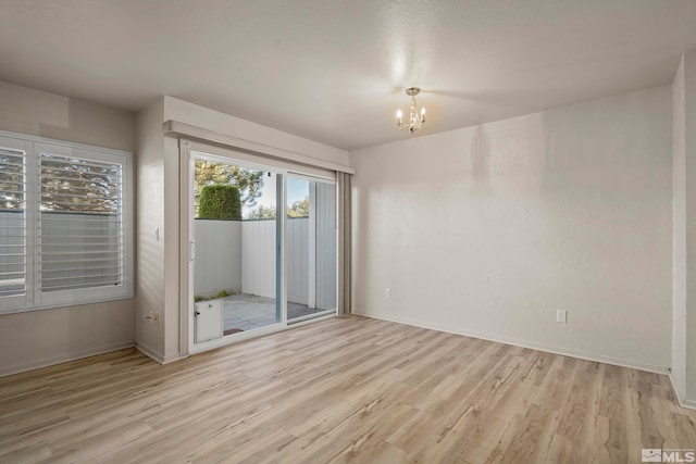 unfurnished room featuring light hardwood / wood-style floors and a chandelier