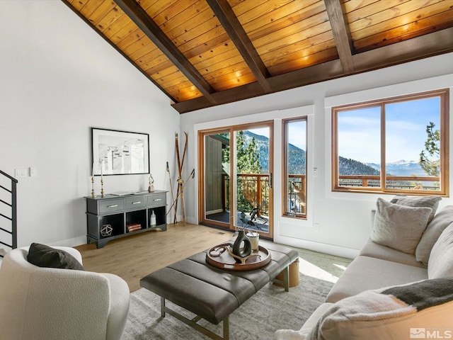 living room with a mountain view, a wealth of natural light, light hardwood / wood-style flooring, and wooden ceiling