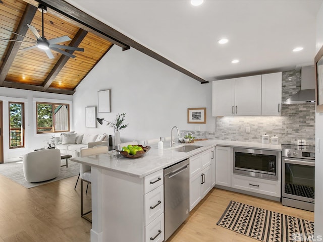 kitchen with vaulted ceiling with beams, white cabinetry, appliances with stainless steel finishes, ceiling fan, and light hardwood / wood-style flooring