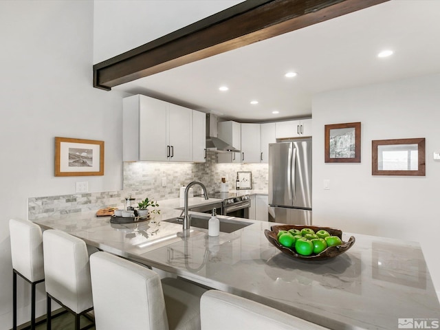 kitchen with kitchen peninsula, a breakfast bar, light stone countertops, white cabinetry, and appliances with stainless steel finishes