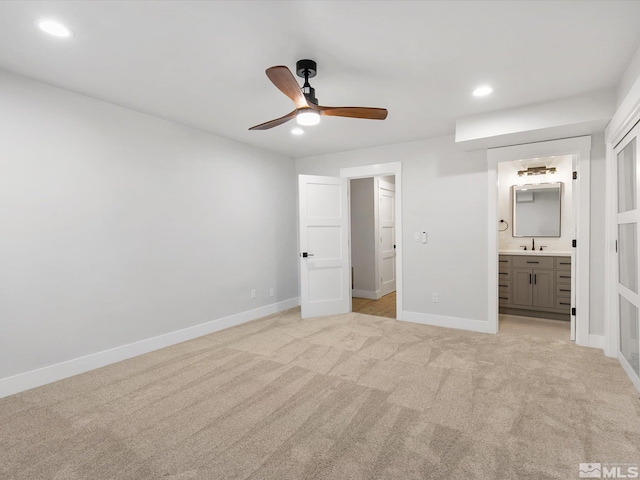 unfurnished bedroom with light colored carpet, ceiling fan, sink, and connected bathroom