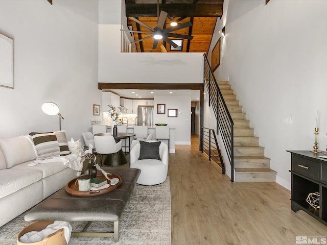 living room featuring a high ceiling, beamed ceiling, hardwood / wood-style flooring, and wooden ceiling