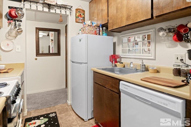 kitchen with white appliances, light tile patterned floors, and sink