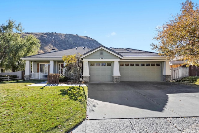 single story home with a mountain view, a garage, a front yard, and covered porch