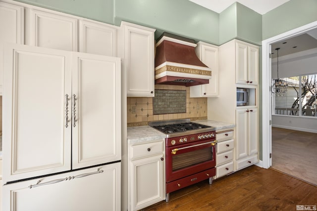 kitchen featuring dark wood-type flooring, an inviting chandelier, custom range hood, white cabinetry, and high end stainless steel range