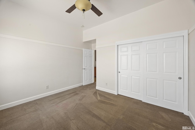 unfurnished bedroom featuring a closet, lofted ceiling, dark carpet, and ceiling fan