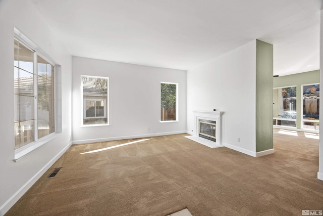 unfurnished living room with plenty of natural light and carpet