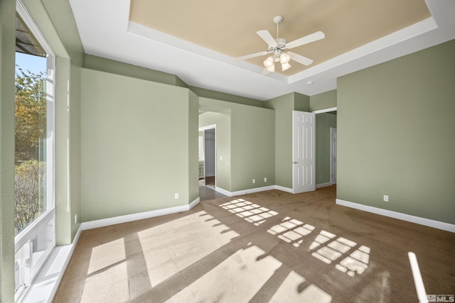 interior space with ceiling fan, carpet floors, and a raised ceiling