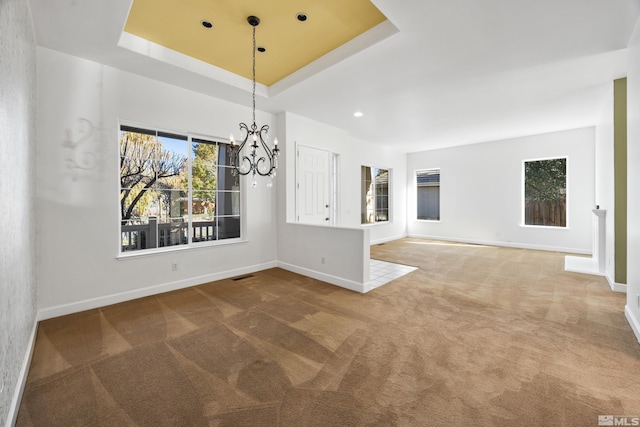 unfurnished dining area featuring carpet flooring, a raised ceiling, and a notable chandelier