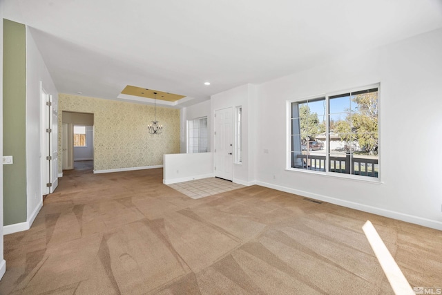 unfurnished room featuring light carpet and a notable chandelier