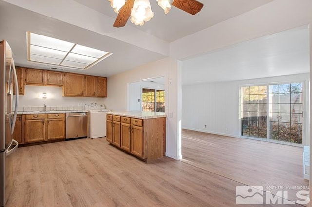 kitchen featuring washer / clothes dryer, plenty of natural light, light hardwood / wood-style flooring, and appliances with stainless steel finishes