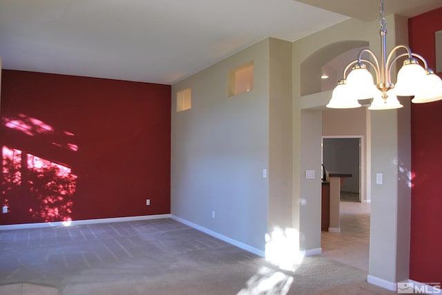 carpeted spare room featuring a notable chandelier