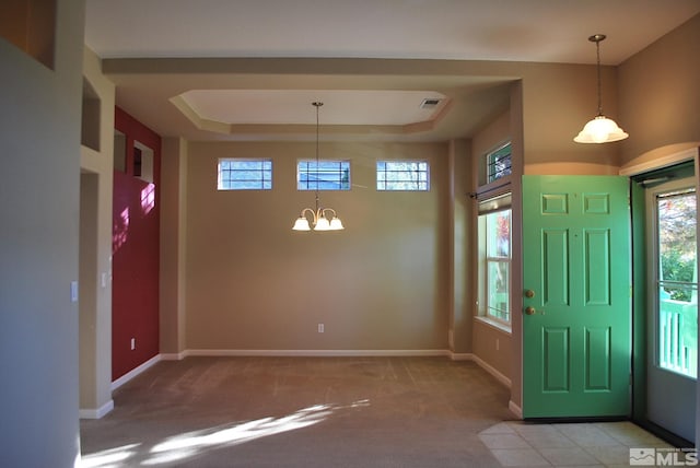 foyer entrance with a chandelier, a tray ceiling, and carpet floors