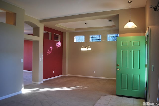 carpeted entryway with a raised ceiling and an inviting chandelier