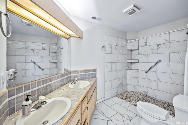 bathroom with tile walls, tiled shower, backsplash, vanity, and toilet