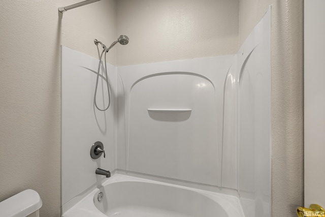 bathroom with washtub / shower combination and toilet