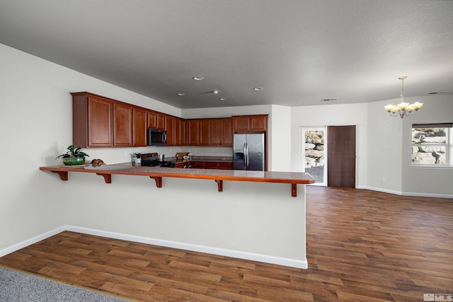 kitchen with a kitchen bar, kitchen peninsula, appliances with stainless steel finishes, and dark wood-type flooring