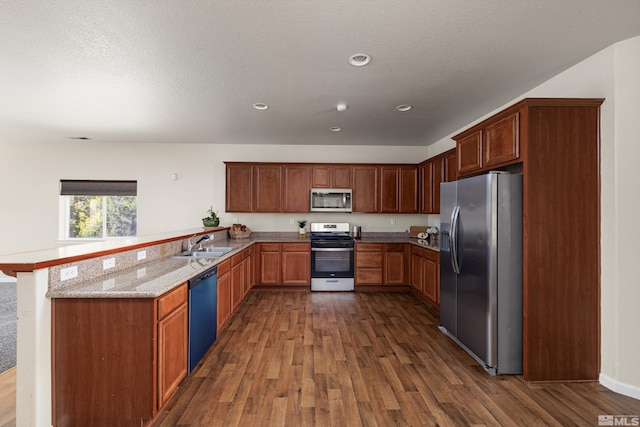 kitchen featuring dark hardwood / wood-style flooring, light stone countertops, kitchen peninsula, and stainless steel appliances