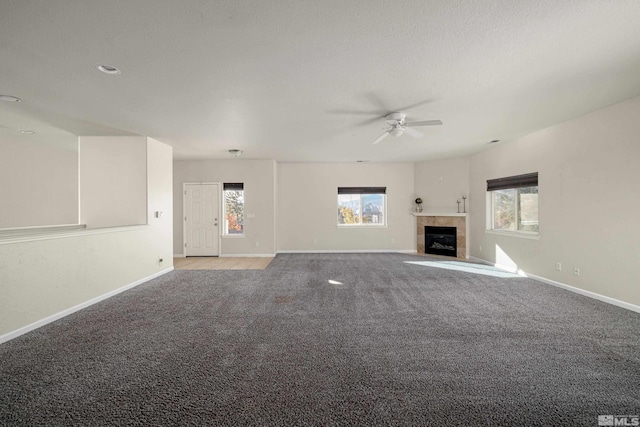 unfurnished living room featuring a fireplace, ceiling fan, a textured ceiling, and carpet