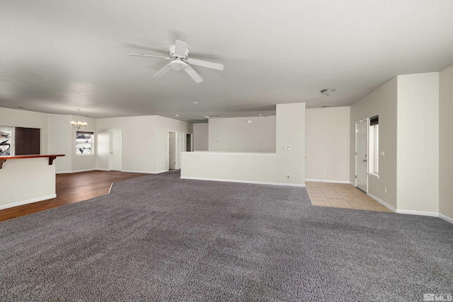 unfurnished living room with ceiling fan with notable chandelier and light hardwood / wood-style flooring