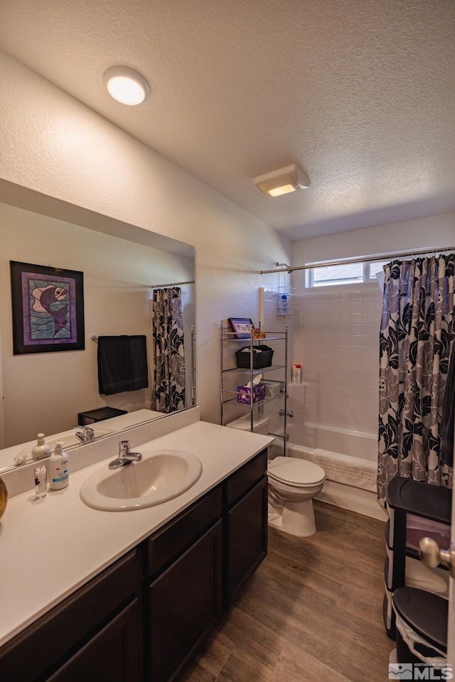 full bathroom featuring shower / bath combination with curtain, vanity, a textured ceiling, hardwood / wood-style floors, and toilet