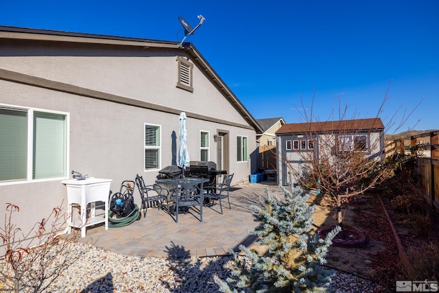 rear view of house with a shed and a patio