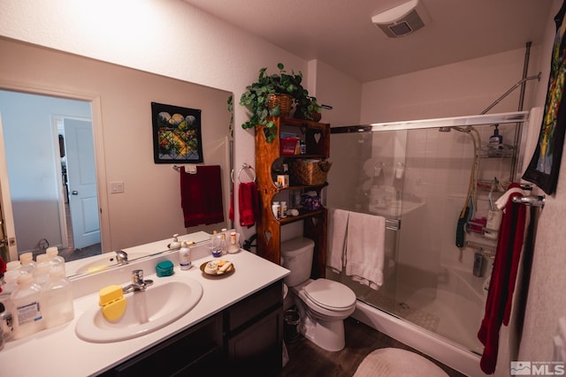 bathroom with hardwood / wood-style floors, vanity, toilet, and a shower with door