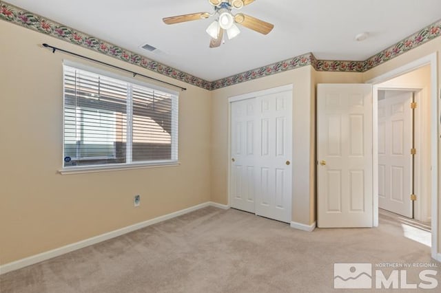 unfurnished bedroom featuring a closet, light colored carpet, and ceiling fan