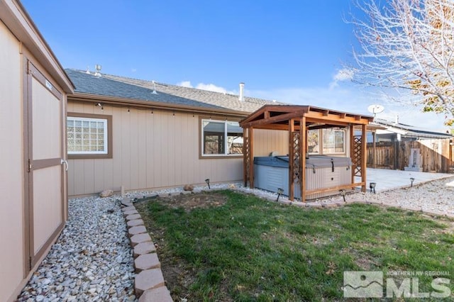 view of side of home with a patio, a yard, and a hot tub