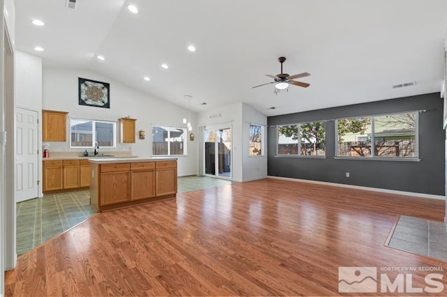 kitchen with light hardwood / wood-style floors, ceiling fan, sink, and a kitchen island